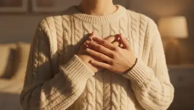 Photorealistic, intimate close-up of a person's hands gently placed over the center of their chest, right above the heart. They are wearing a soft, beige knitted sweater. The lighting is warm, golden, and comforting, suggesting self-compassion, emotional healing, and vulnerability. Soft focus background, highly emotive.