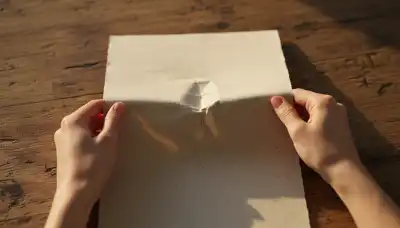 Una escena serena de unas manos delicadas doblando y rasgando suavemente un papel texturizado de alta calidad sobre una mesa de madera rústica. Iluminación cinematográfica que resalta dramáticamente las texturas crujientes del papel y las vetas de la madera. La imagen evoca el placer táctil y auditivo de los 'crisp sounds' del ASMR, con una paleta de colores cálidos y terrosos.