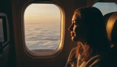 Cinematic photography of a person looking thoughtfully out of an airplane window at a vast expanse of white clouds. Warm sunlight is illuminating their face, conveying a sense of emotional release and mental clarity after a dopamine detox. High contrast, beautiful lighting, shot on 35mm lens.