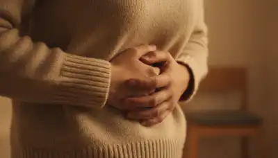 Close-up photorealistic shot of a person's hands tightly clasping their own stomach over a cozy knitted sweater, conveying a feeling of hidden anxiety or a knot in the stomach. Warm indoor lighting, shallow depth of field, sharp focus on the hands and fabric textures, cinematic and emotional lifestyle photography.