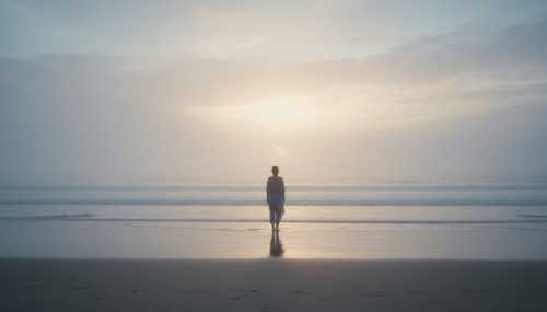 Photorealistic, atmospheric landscape photography reflecting inner calm and integrated grief. A lone figure standing on a vast, misty beach at dawn, looking out at a tranquil, expansive ocean. Muted color palette with soft blues, greys, and a gentle hint of morning light breaking through the clouds. Evocative, deeply moving, symbolizing the vastness of the human heart containing sorrow.