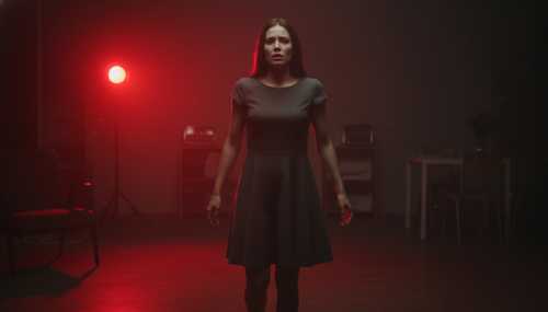 A photorealistic image of a woman standing completely frozen in a dimly lit room, illuminated by a subtle, urgent red glow that symbolizes the brain's 'Code Red' amygdala hijack. Her expression shows a mix of sudden anxiety and emotional paralysis. Cinematic, tense atmosphere.