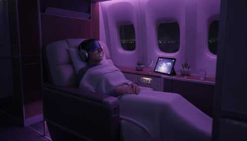 An first-class airplane cabin at night with soft ambient purple mood lighting. A passenger wearing high-quality noise-canceling headphones, a premium silk eye mask, and a subtle transparent mouth tape, sleeping deeply and peacefully. Ultra-detailed, cinematic.